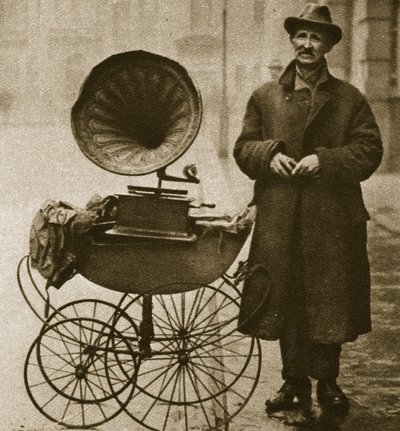 Een straatverkoper vermaakt met een grammofoon, vervoerd in een kinderwagen door English Photographer